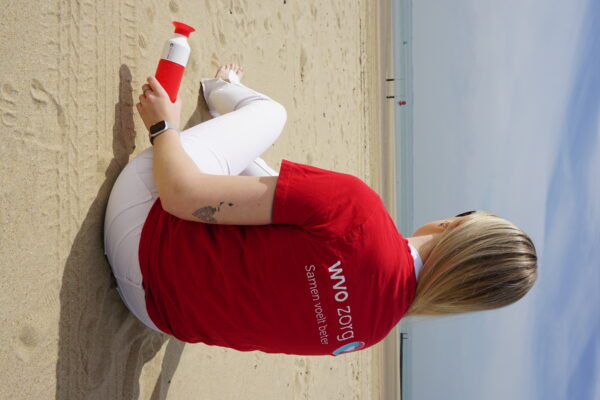 eBirds & Zomerzorg - vrouw met rood shirt zit op het strand