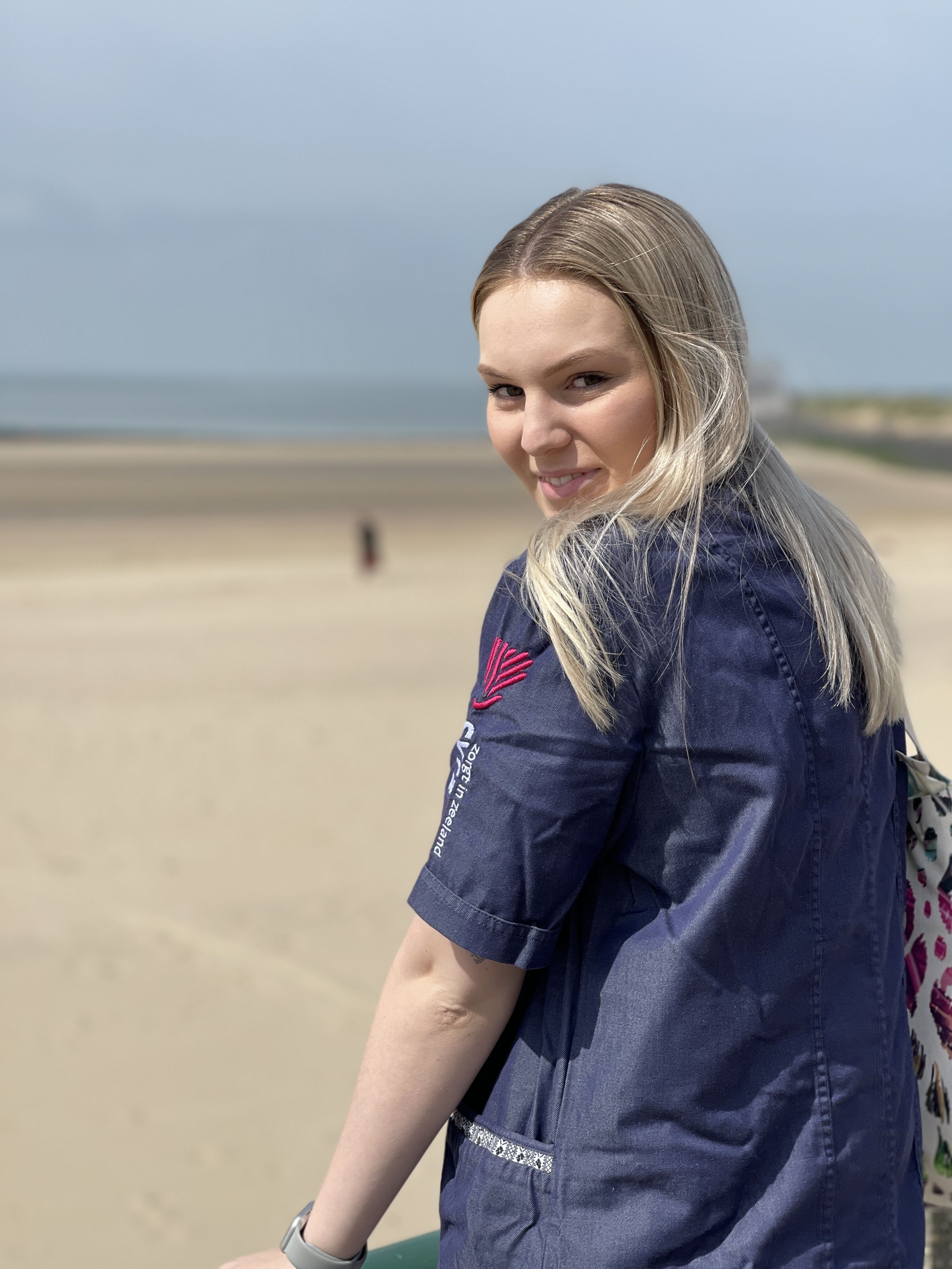 eBirds & Zomerzorg - meisje kijkt naar achter en lacht voor het strand