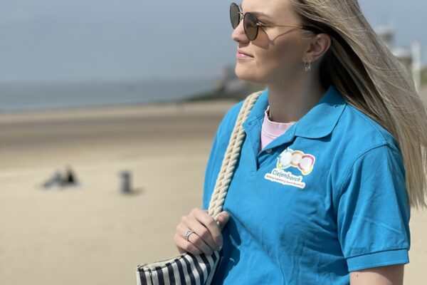 eBirds & Zomerzorg - vrouw staat in de zon met een blauw shirt voor het strand
